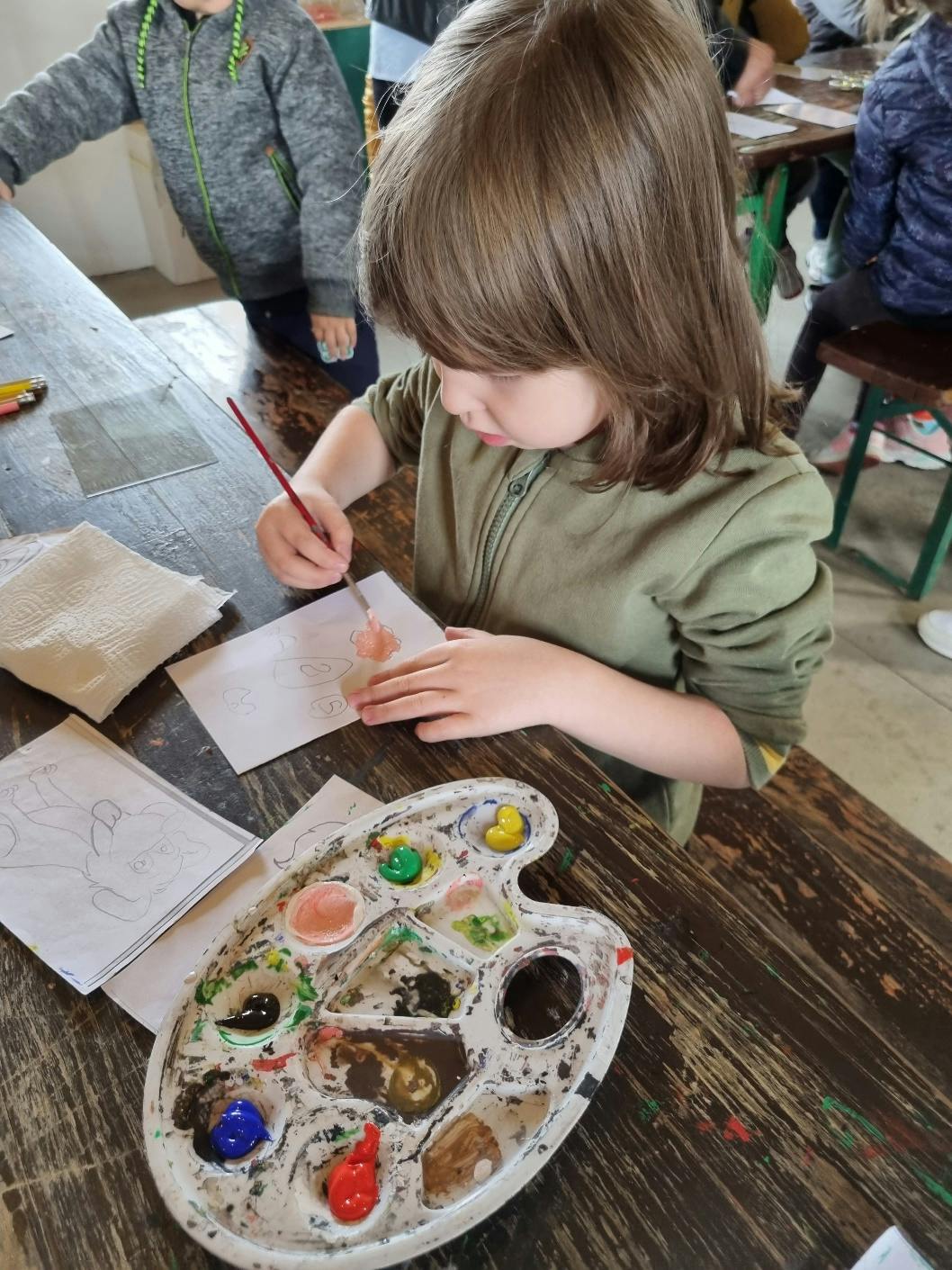 Przedszkolaki w Stacji Basznia i Kresowej Osadzie | Dziewczynka maluje farbami przy stole.jpg