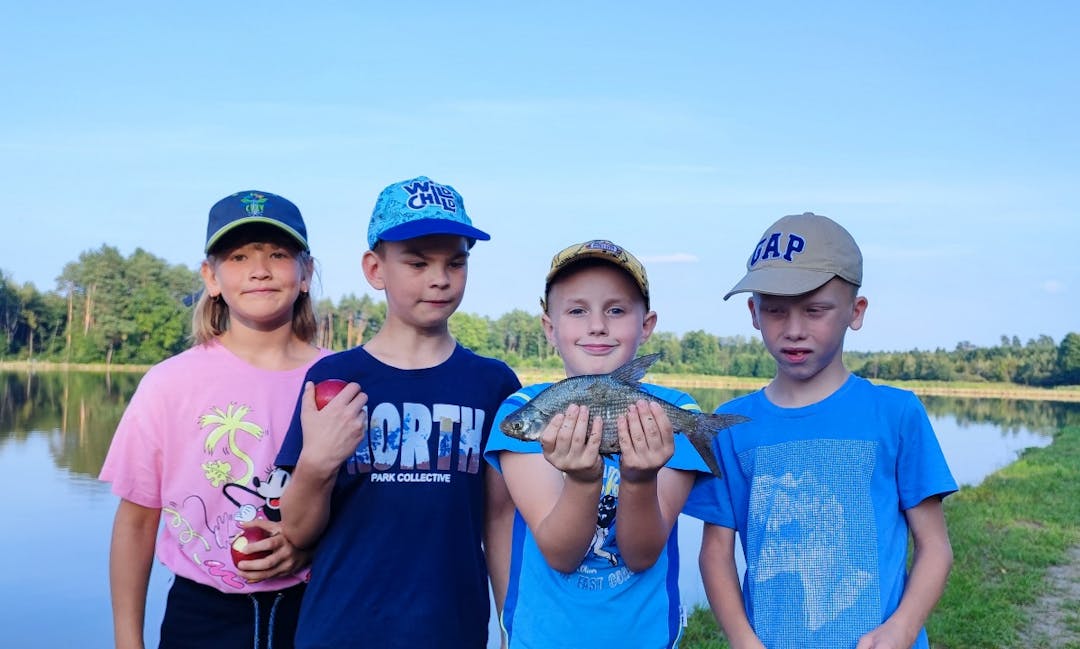 Wędkowanie w Korzenicy | Trzech chłopaków i jedna dziewczynka pozują do zdjęcia z rybą.jpg