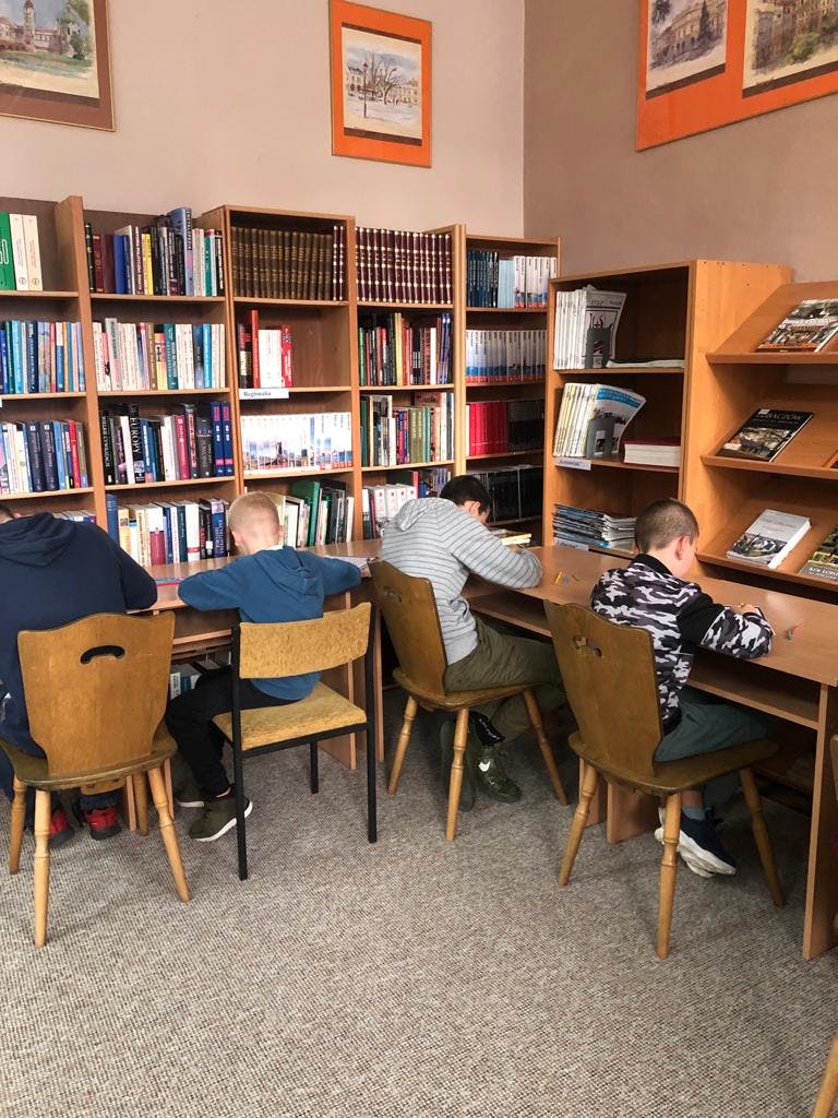 Pozalekcyjne zajęcia w bibliotece | Uczniowie siedzą przy stolikach.jpg