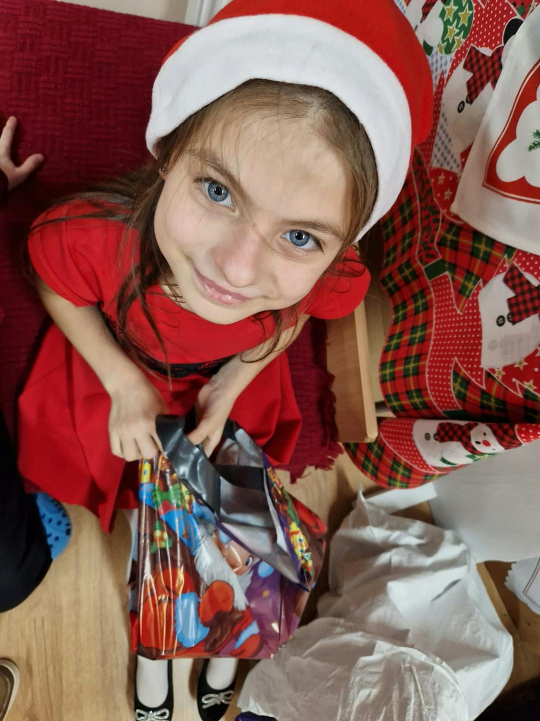 Niezapomniane spotkanie z Mikołajem! | Dziewczynka w czapce mikołaja uśmiecha sie do kamery.jpg