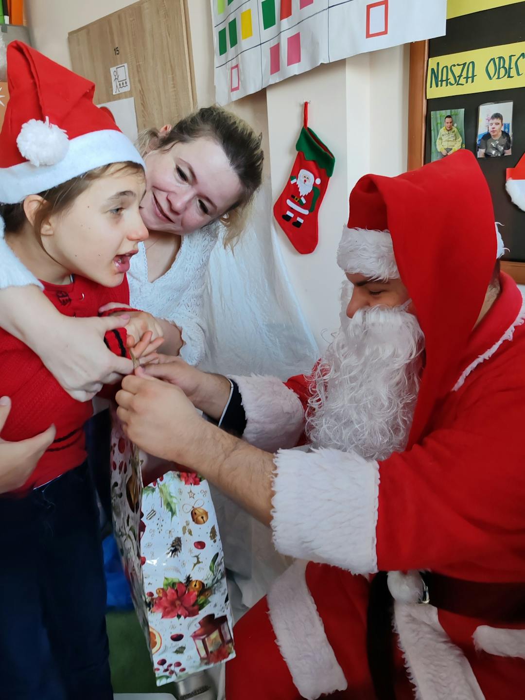 Niezapomniane spotkanie z Mikołajem! | Dziewczynka z nauczycielką przyjmują prezent od Mikołaja.jpg