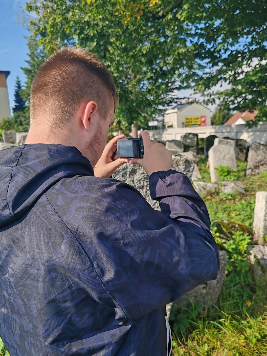 Nieznany Lubaczów | Uczeń z aparatem robi zdjęcia na cmentarzu.jpg