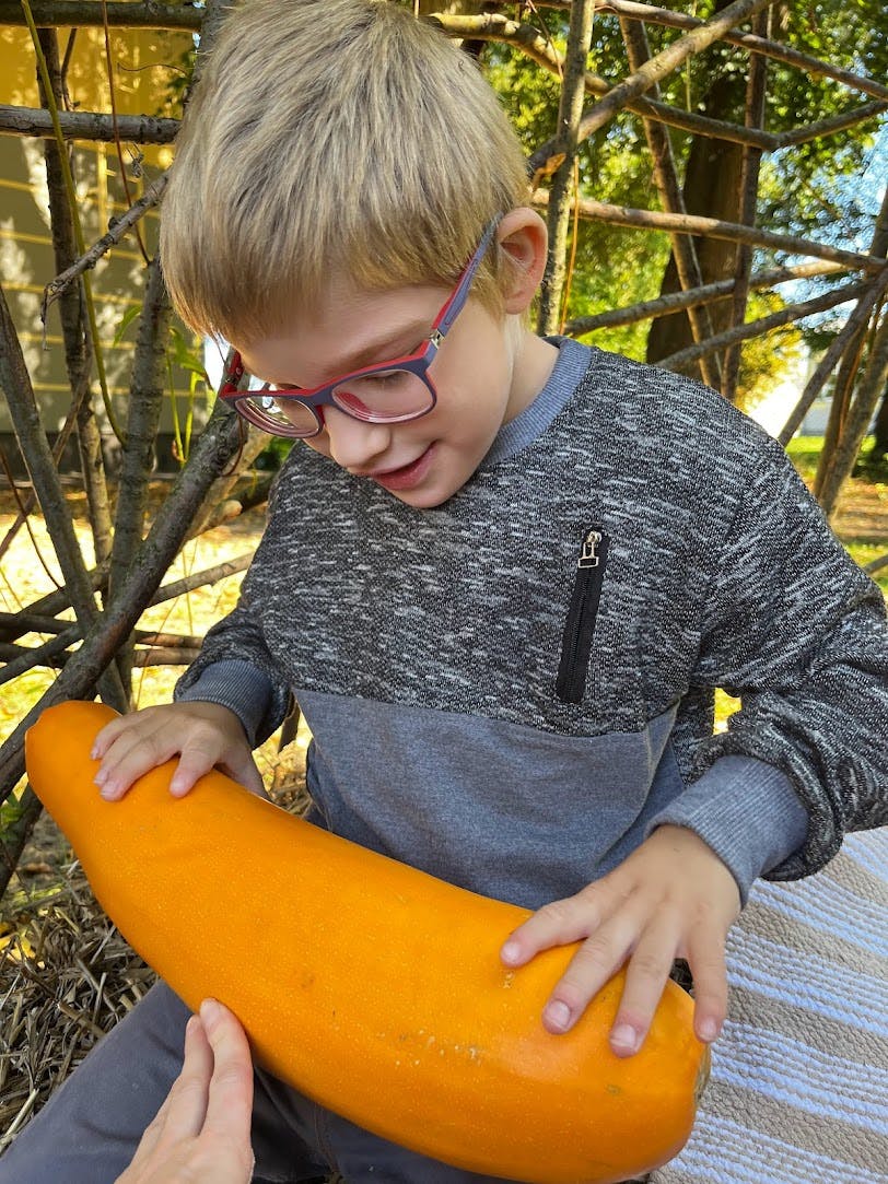 Powitanie Jesieni | chłopiec w okularach ogląda pomarańczową cukinie.jpg