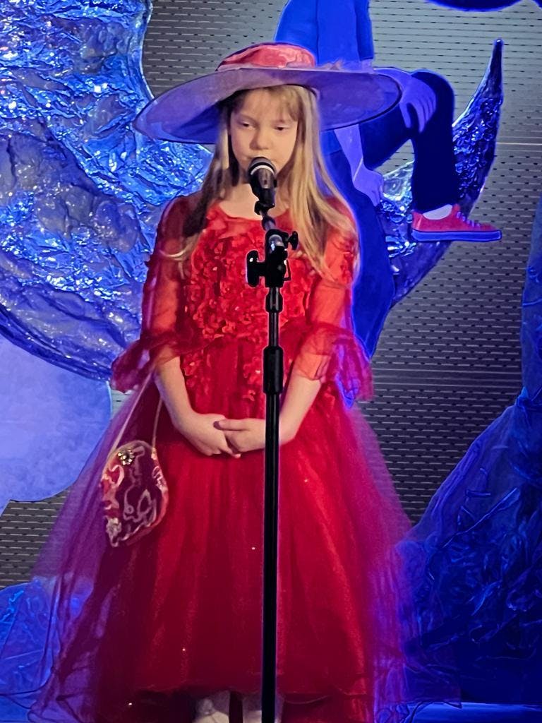 Konkurs recytatorski w Leżajsku | Uczennica w czerwonej sukience mówi do mikrofonu.jpg