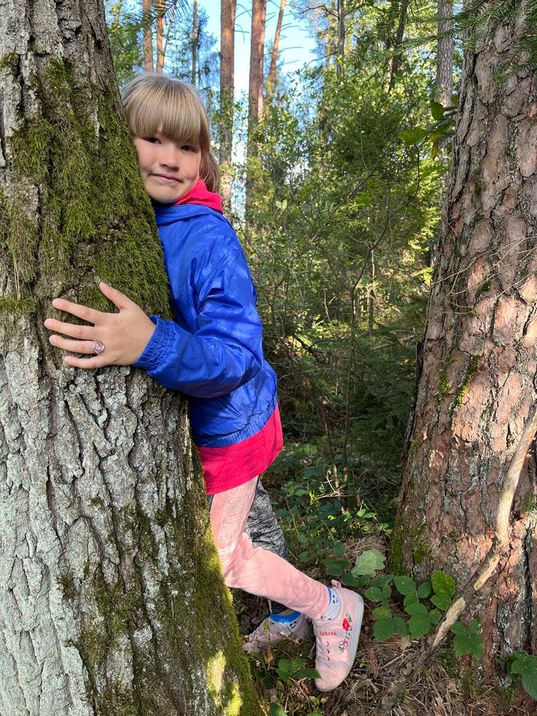 W rezerwacie przyrody Jedlina | dziewczynka obejmuje drzewo w lesie.jpg