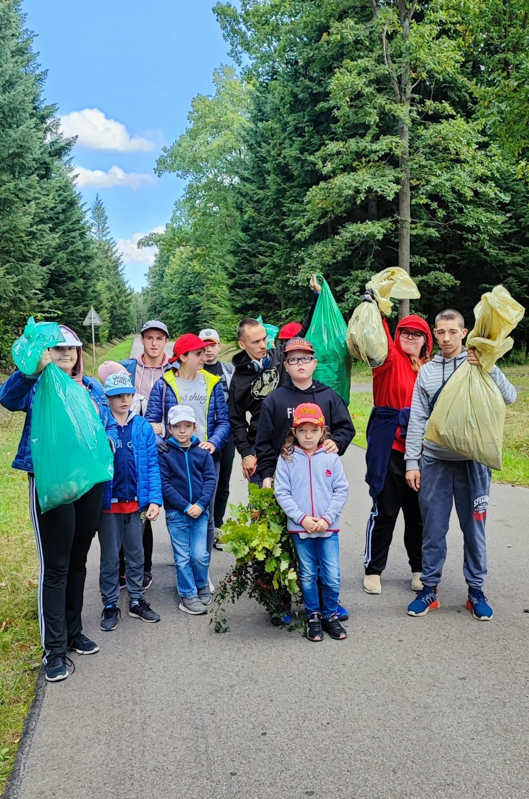 W rezerwacie przyrody Jedlina | dzieci pokazują zebrane śmieci w workach w tle las.jpg