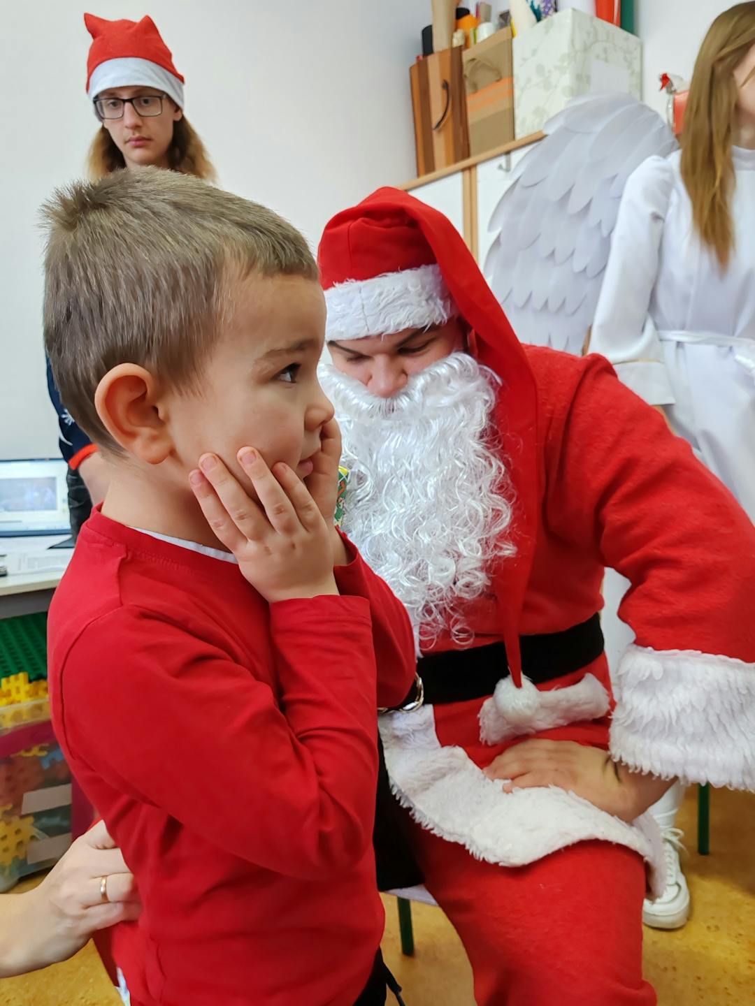 Niezapomniane spotkanie z Mikołajem! | Chłopiec trzyma rece na policzkach, w tle Mikołaj.jpg