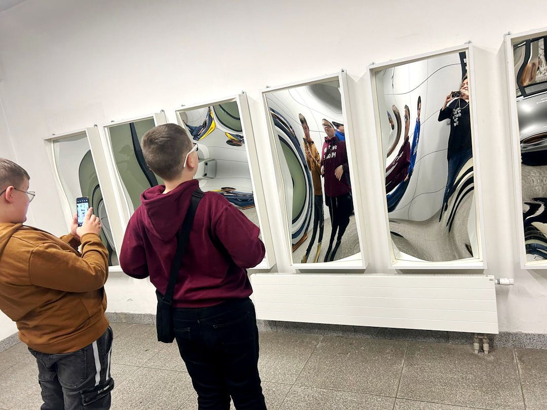 Szklane dziedzictwo Krosna | dwóch chłopców przygląda się w krzywych lustrach.jpg