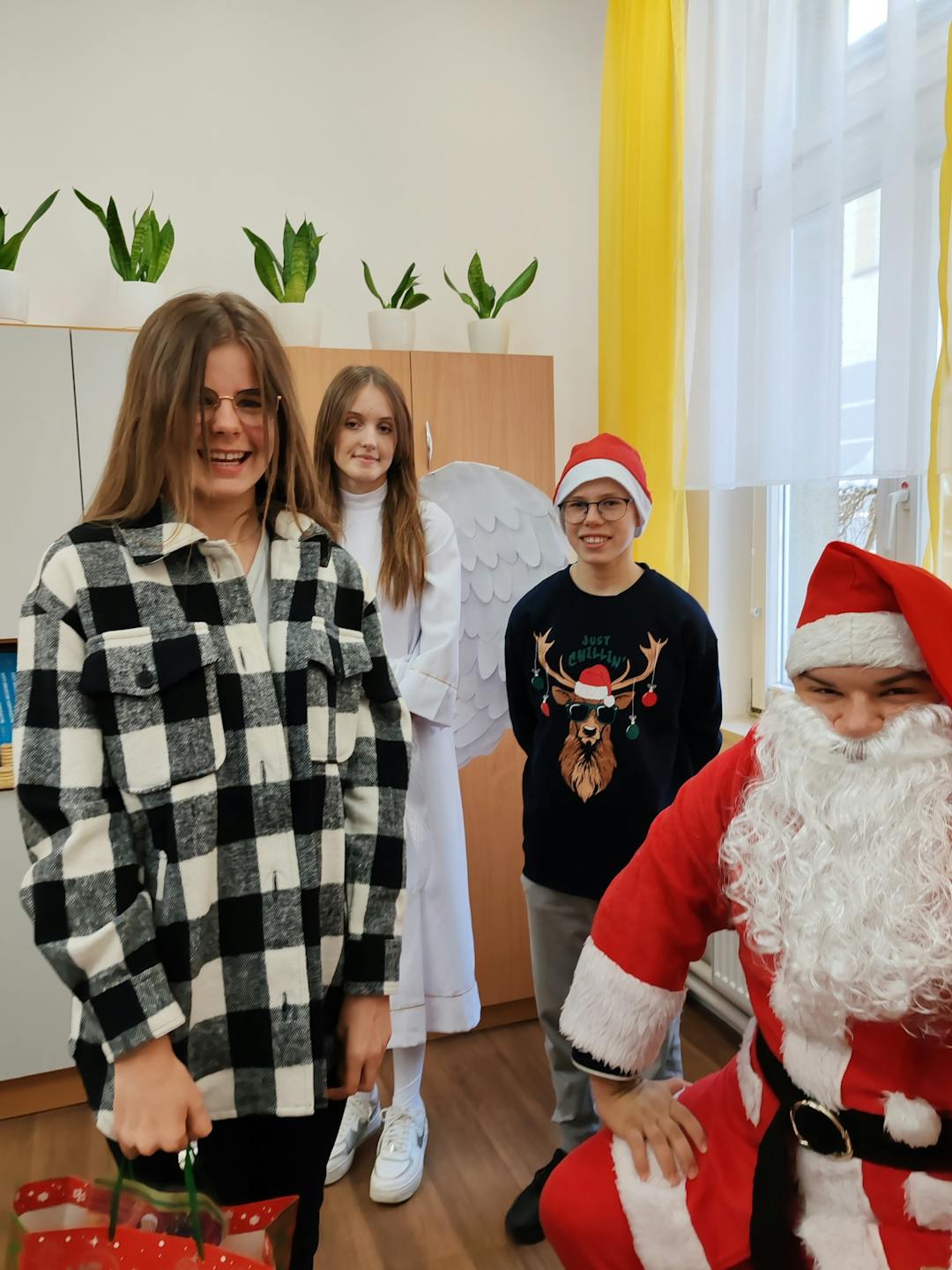 Niezapomniane spotkanie z Mikołajem! | Uczennica w koszuli w kratę przyjmuje prezent od Mikołaja.jpg