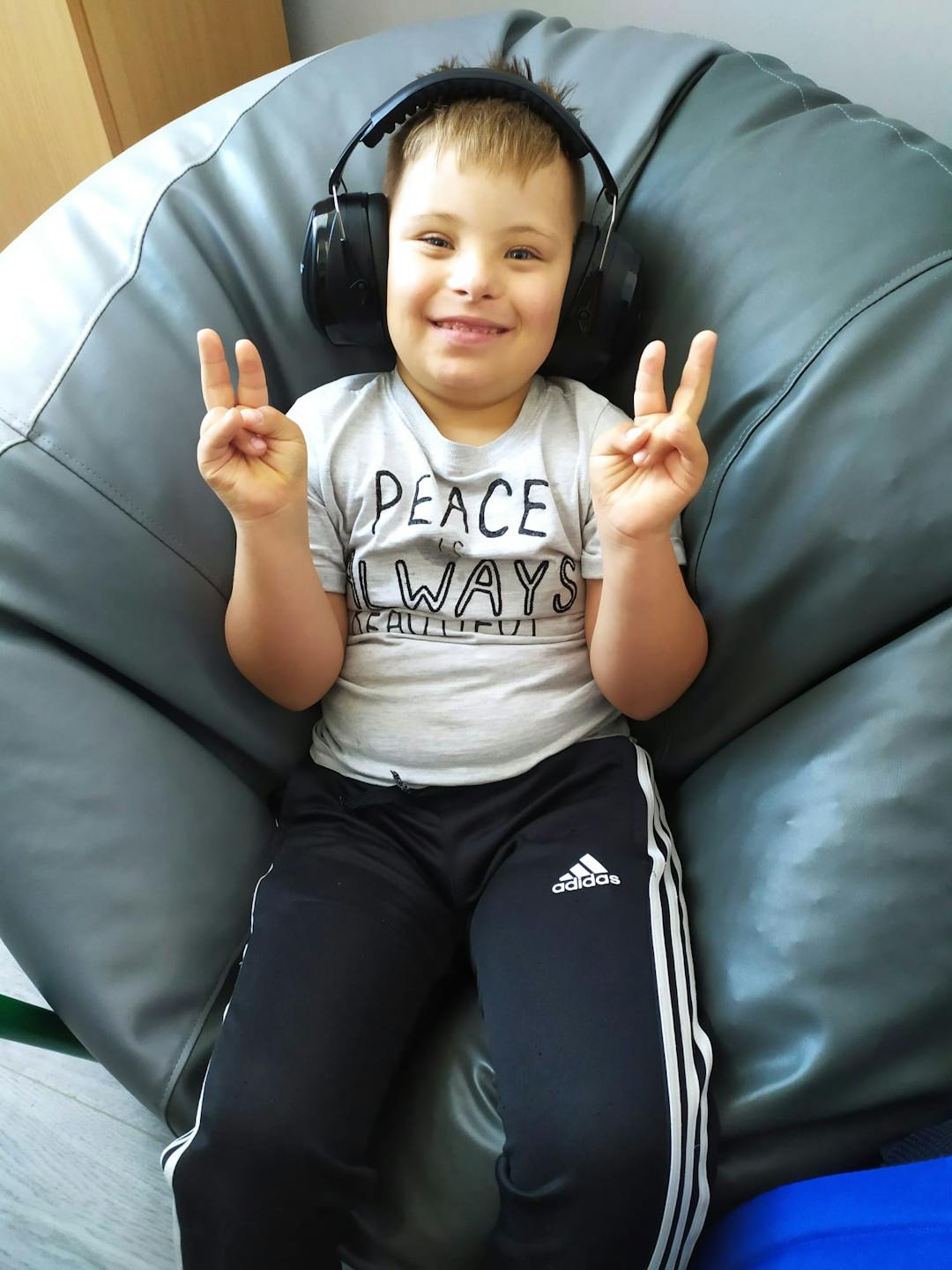 „Przyjazna przystań” | Uśmiechnięty chłopiec ze słuchawkami na uszach siedzi na fufie.jpg
