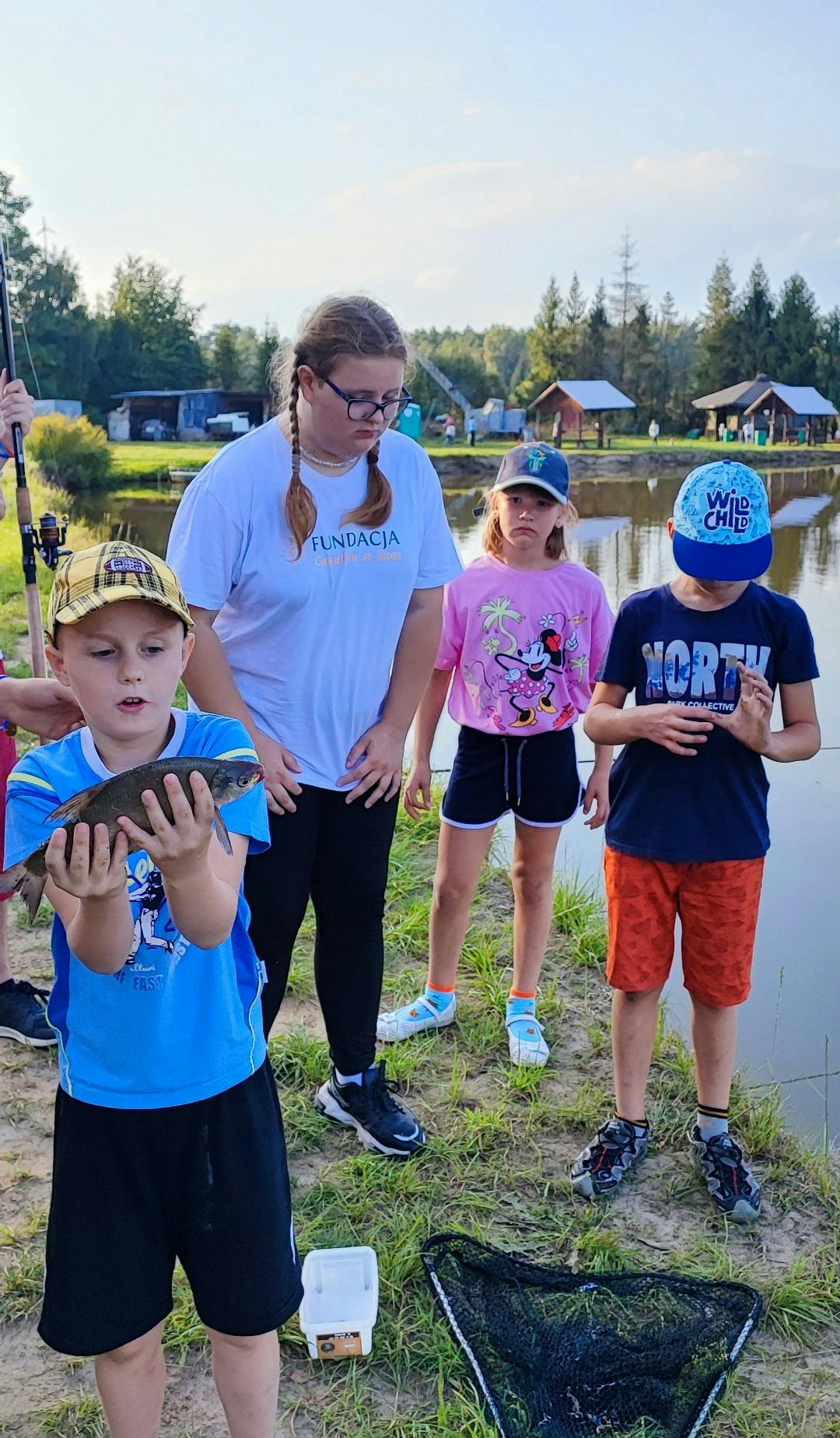 Wędkowanie w Korzenicy | Czworo dzieci pozuje do zdjęcia z rybą.jpg