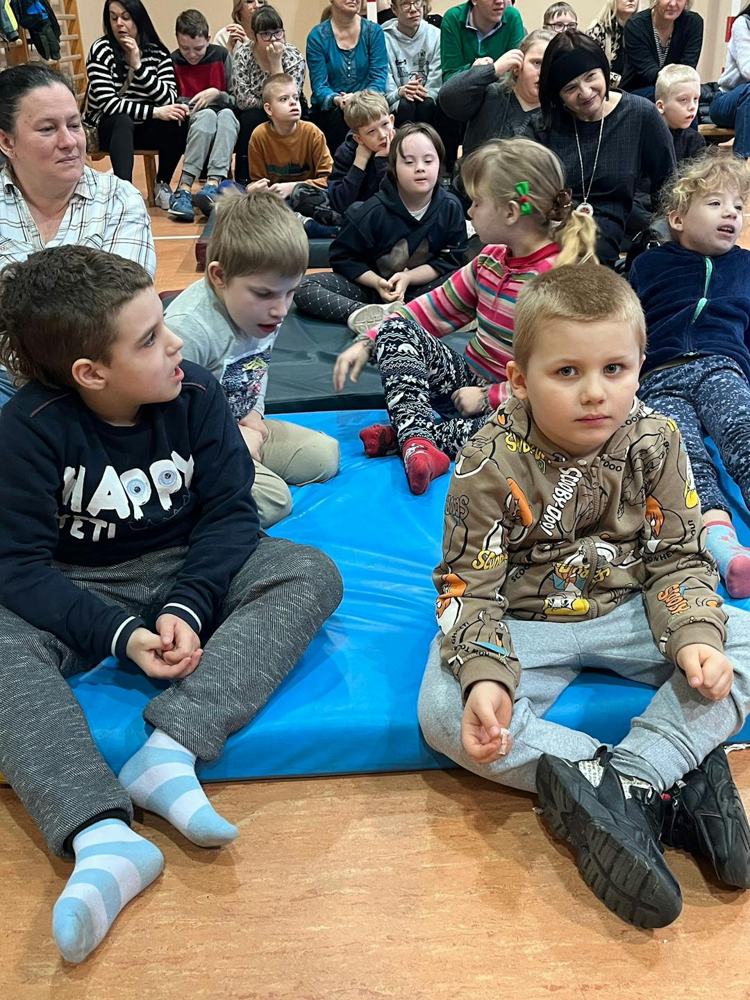Spektakl interaktywny „Bocian i Żabka” | Grupa dzieci siedzi na materacach.jpg