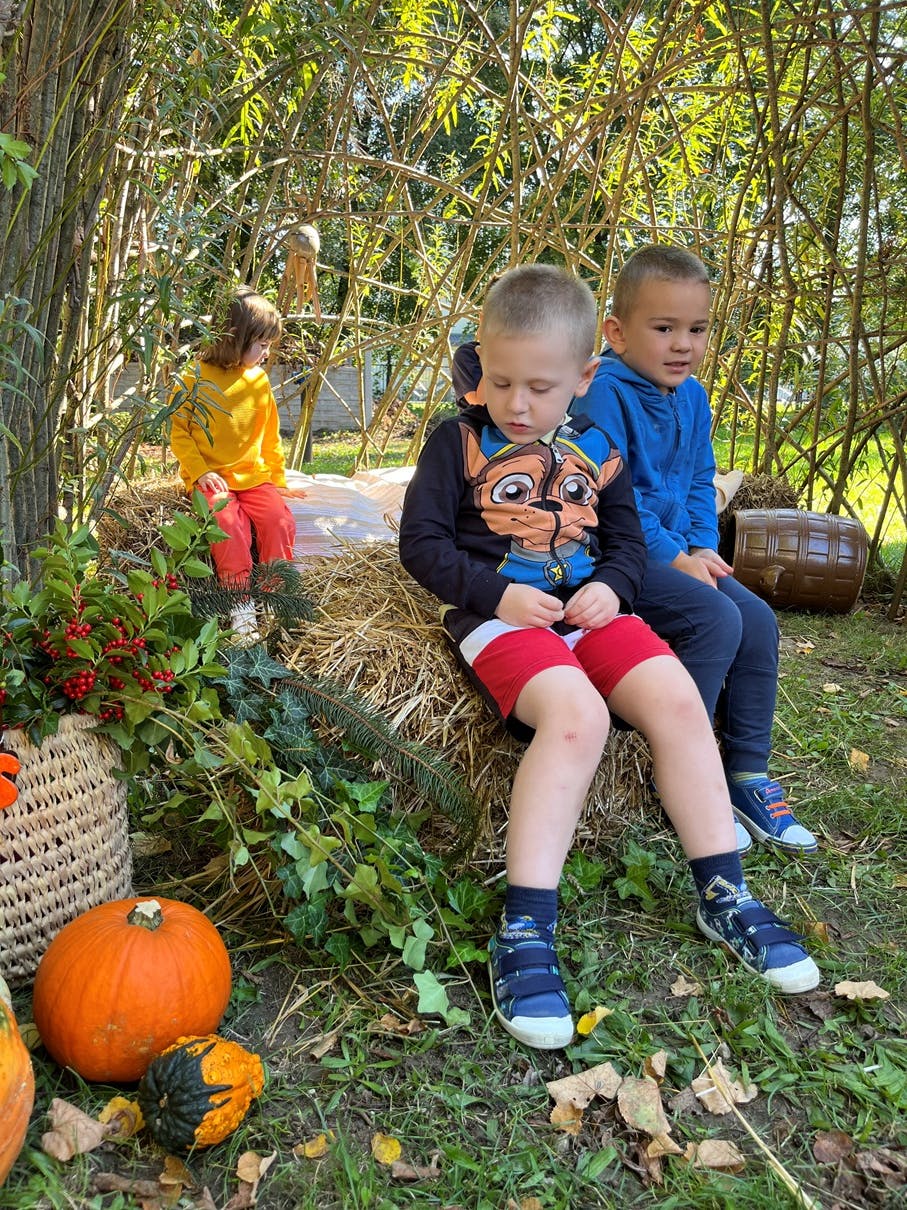 Powitanie Jesieni | Dwóch chłopców siedzi na kostce ze słomy, obok dynia i inne jesienne dekoracje.JPG
