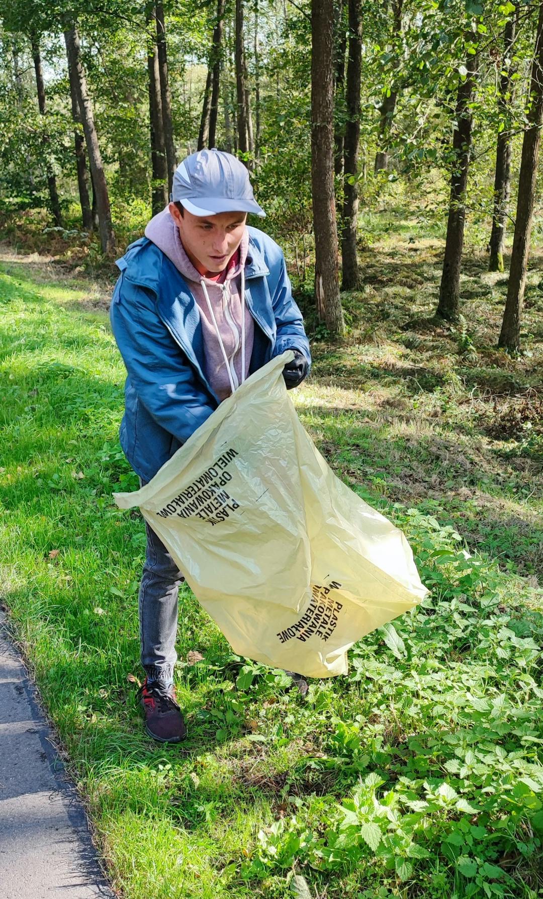 W rezerwacie przyrody Jedlina | chłopiec zbiera śmieci do worka.jpg