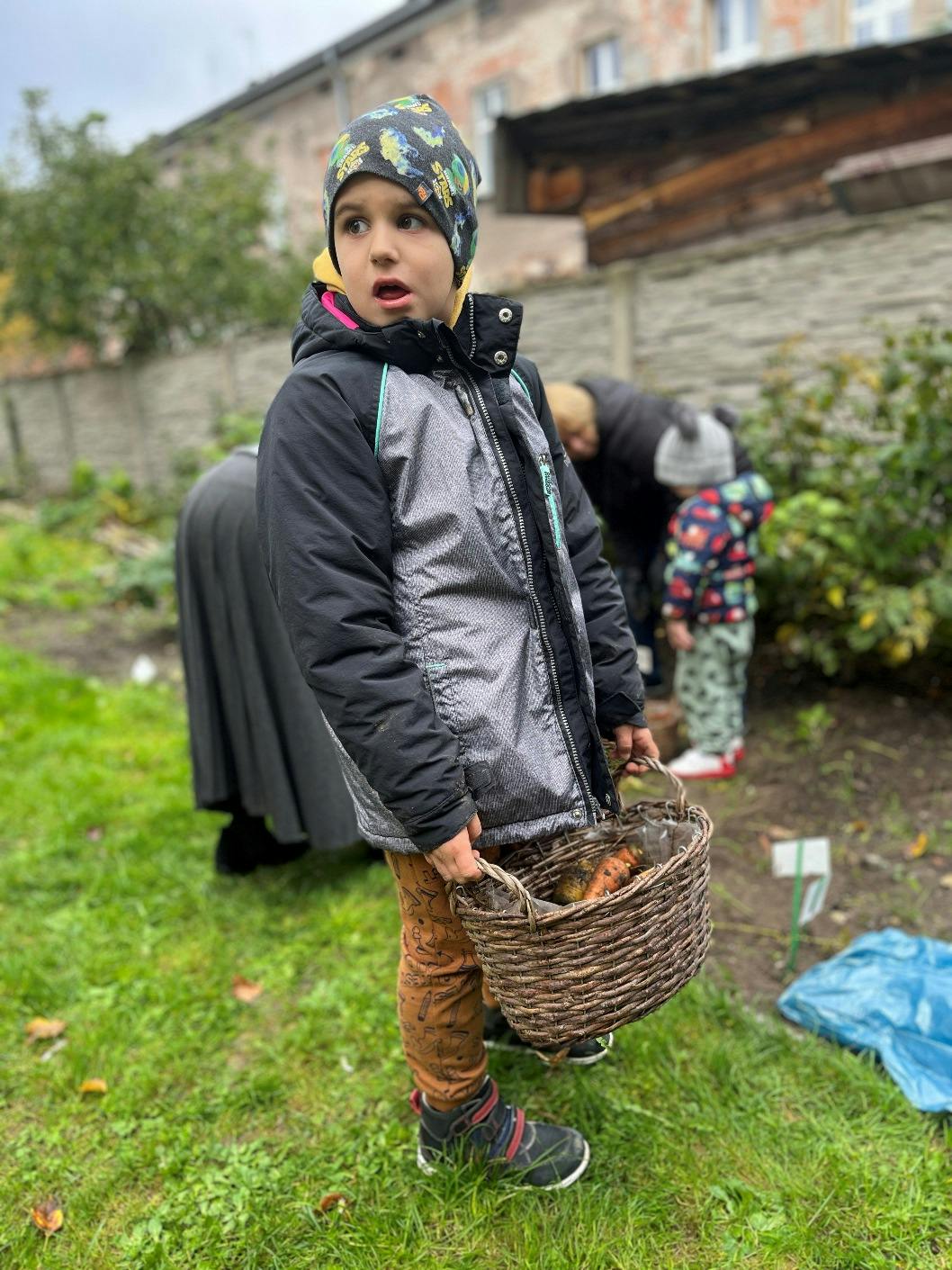 Jesienne prace w ogrodzie | Chłopiec w ogrodzie trzyma koszyk z marchewkami.jpeg