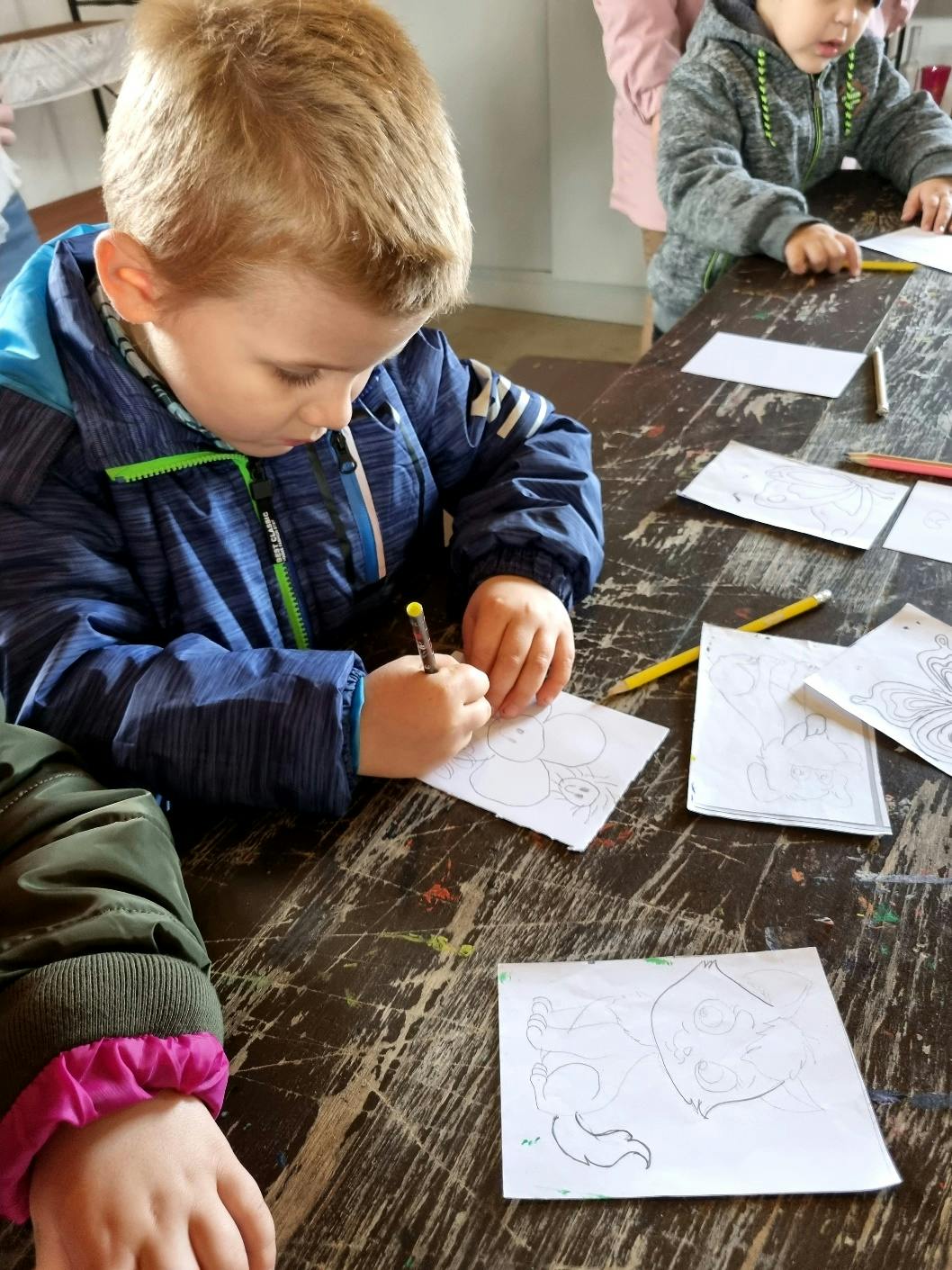 Przedszkolaki w Stacji Basznia i Kresowej Osadzie | Chłopiec rysuje przy stole.jpg