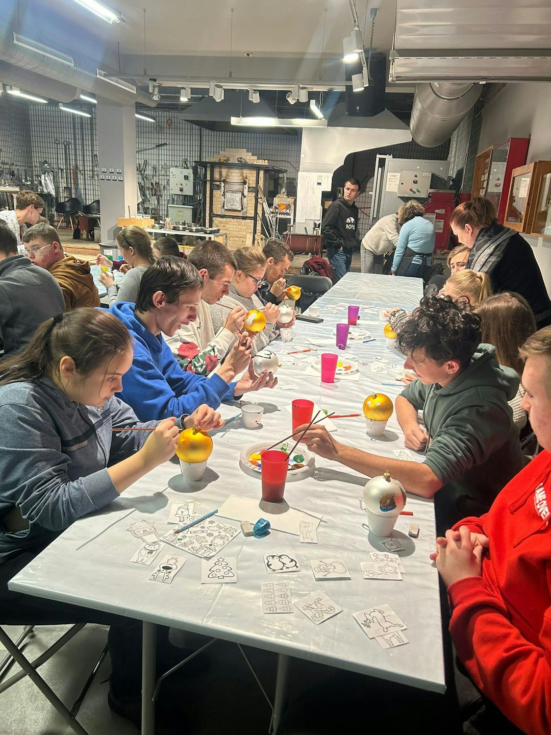 Szklane dziedzictwo Krosna | Uczniowie przy stole malują szklane bombki.jpg