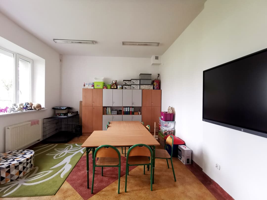 „Przyjazna przystań” | Klasa z dużym stołem na środku. Po prawj wisi tablica mutimedialna, w tle szfy.jpg
