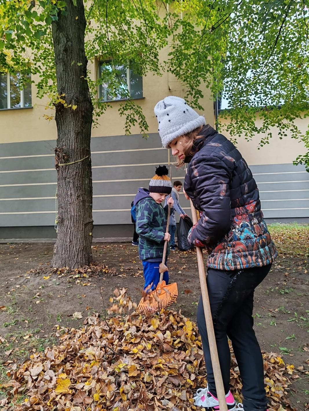 Jesienne prace w ogrodzie | Uczniowie grabią liście w ogrodzie.jpg