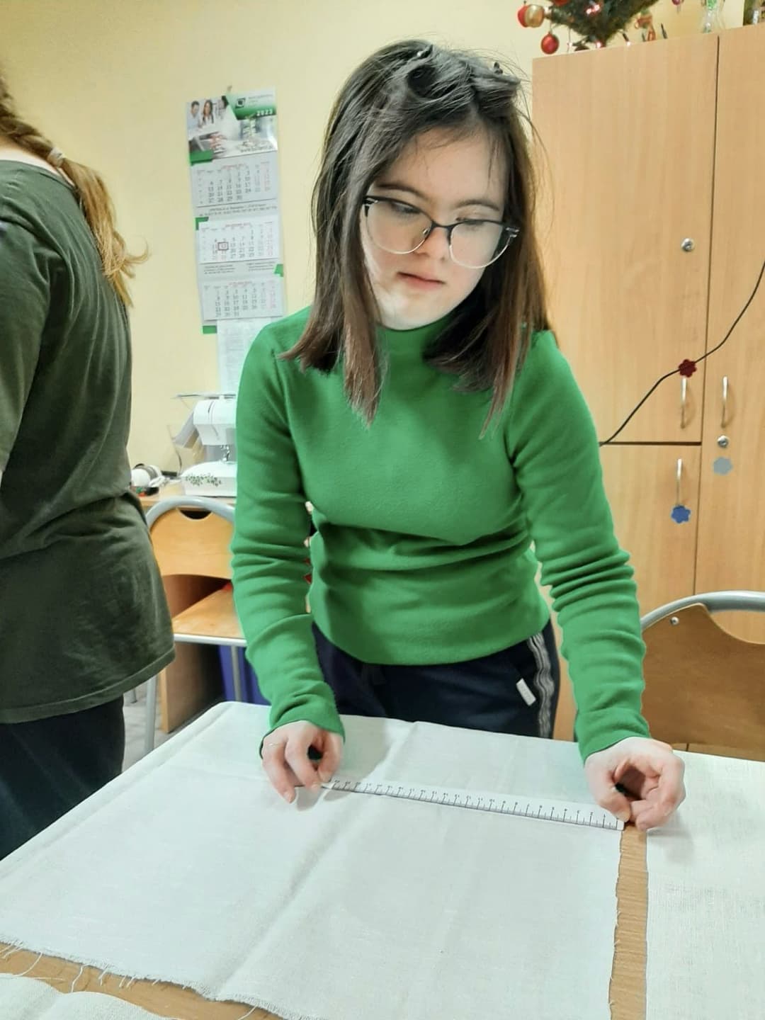 Zajęcia krawieckie w internacie | Dziewczyna mierzy materiał.jpg