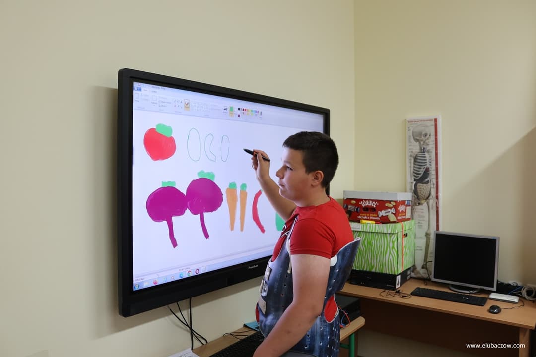 „Przyjazna przystań” | uczeń w gorsecie rysuje na tablicy multimedialnej.jpg