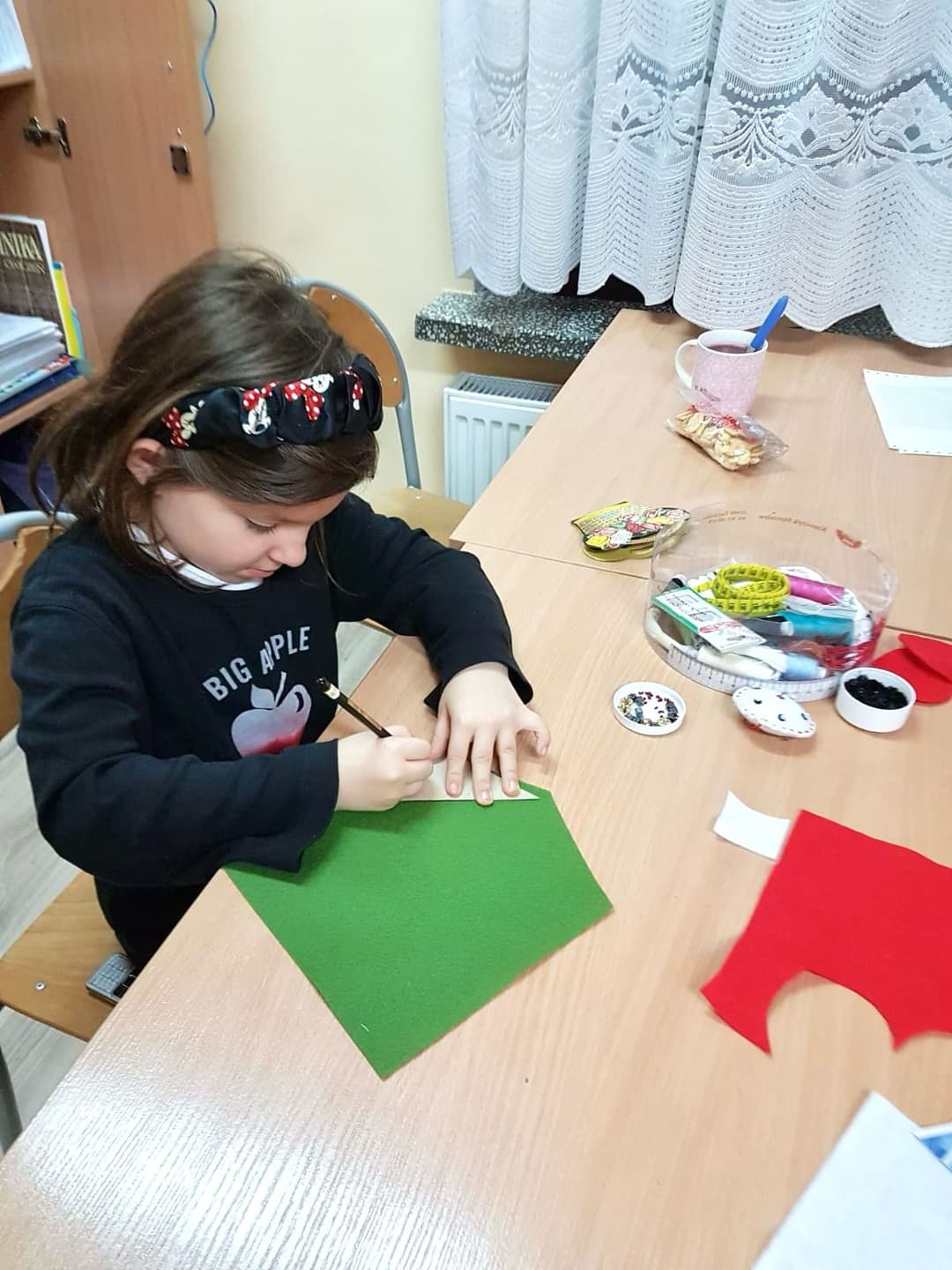 Zajęcia krawieckie w internacie | Dziewczynka odrysowuje szablon na materiale.jpg