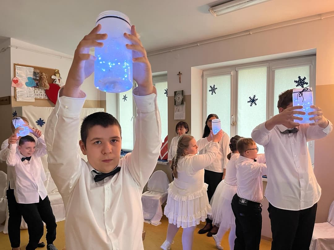 Między światłem, a ruchem… | Uczniowie podczas wystepu podnoszą lampiony do góry.jpg