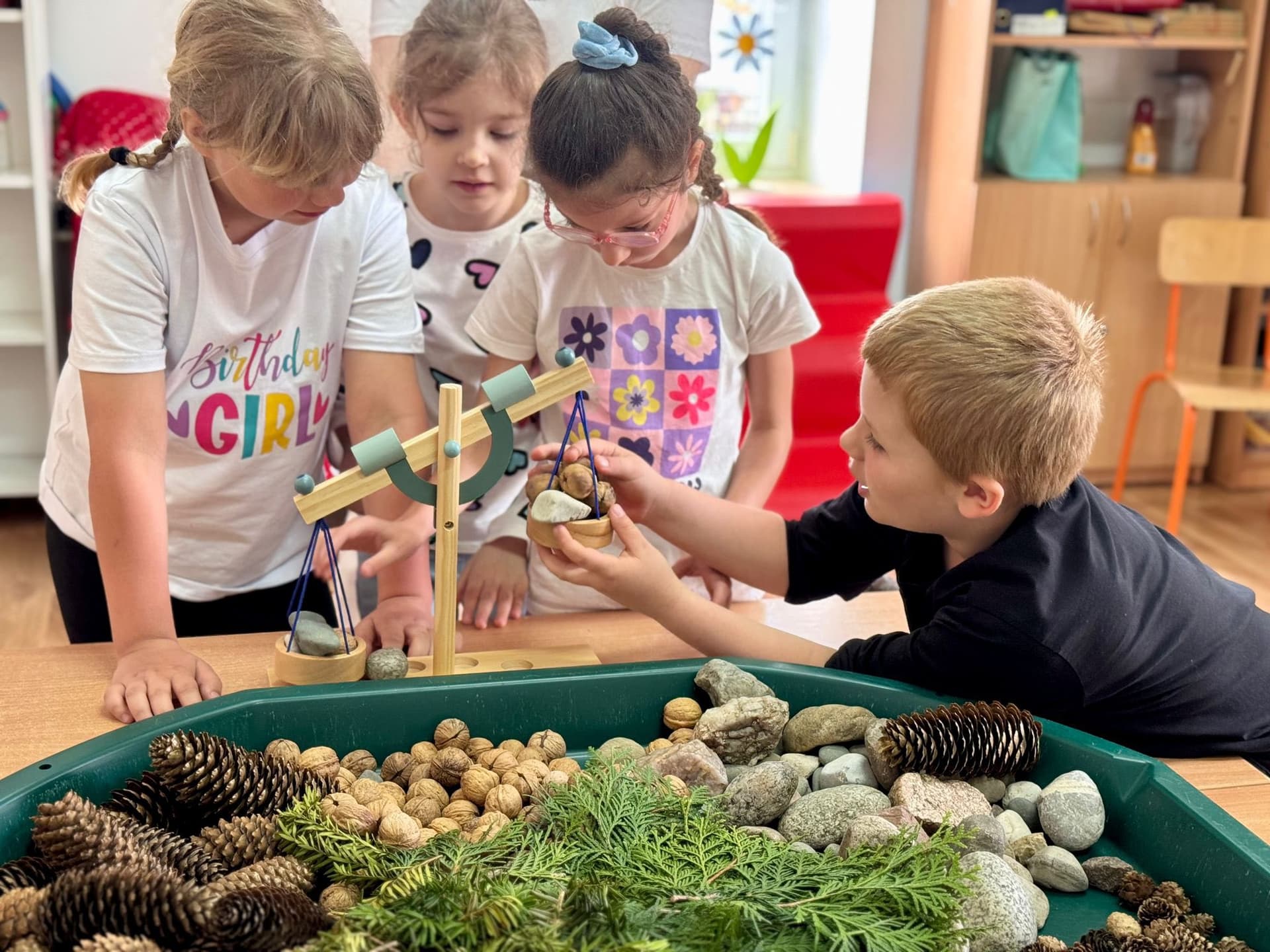 Rosnę z matematyką | GŁÓWNE_Dzieci nad pojemnikiem z materiałami naturalnymi i małą wagą.jpg