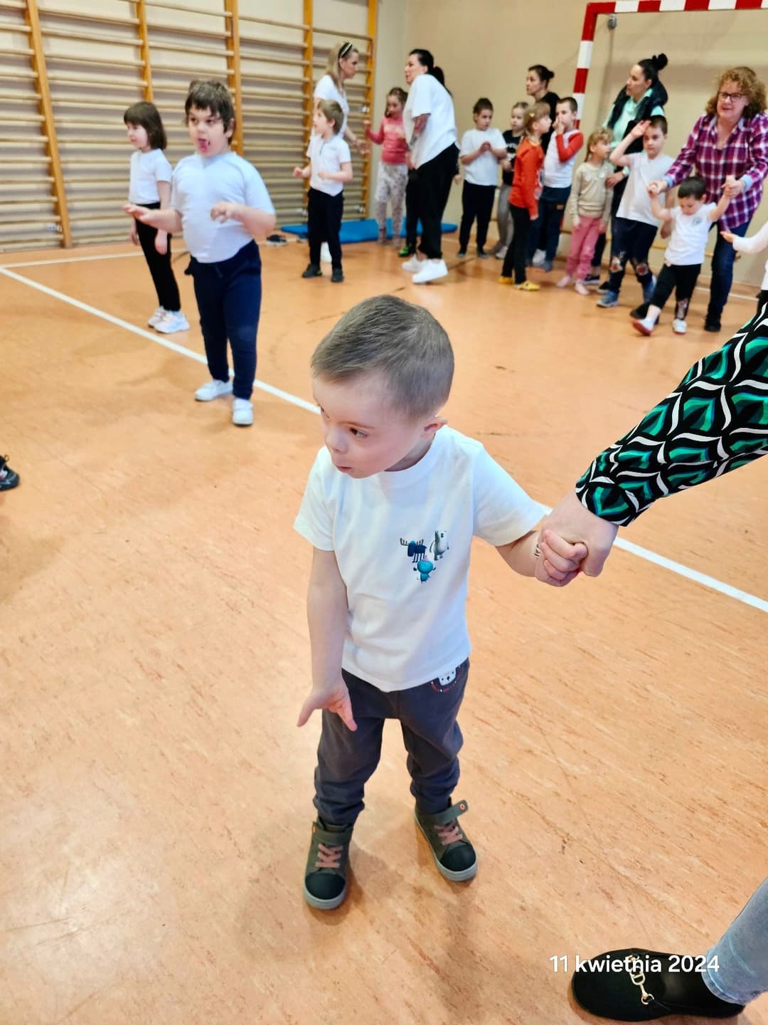 Ćwiczenia ruchowe z mistrzynią Polski w kickboxingu | Mały chłopiec stoi na środku sali, w tle inne dzieci.jpg