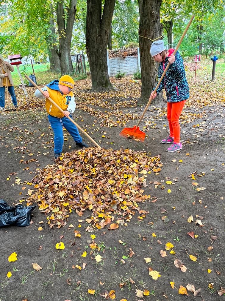 Jesienne prace w ogrodzie | Dwoje uczniów grabi liście w ogrodzie.jpeg