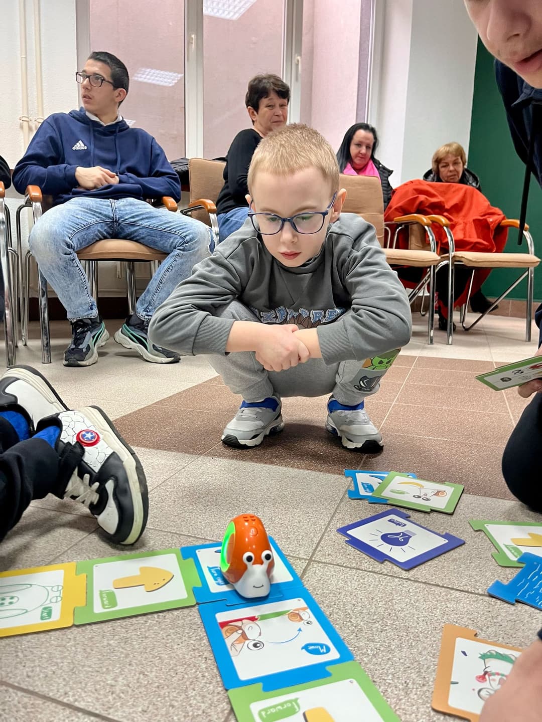 ROBOTYKA | Chłopiec przygląda się ślimakowi, który jeździ po kolorowych kartach.jpg