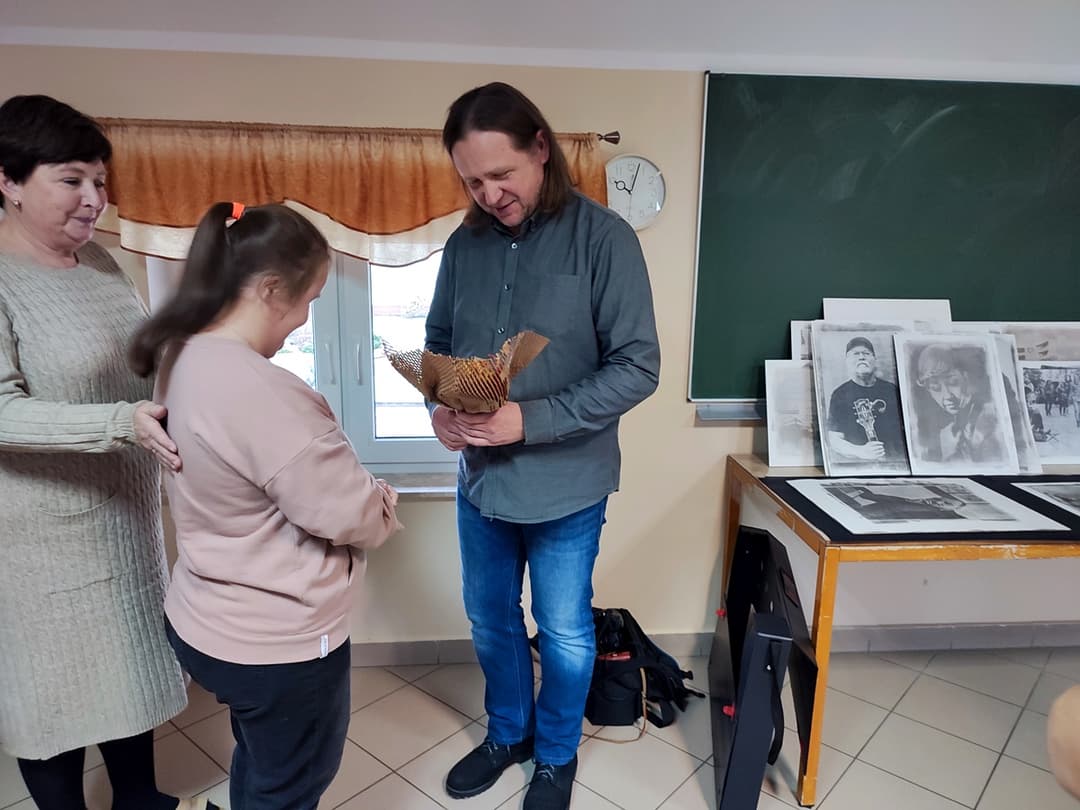 W świecie sztuki | uczennica wręcza prezent mężczyźnie.jpg