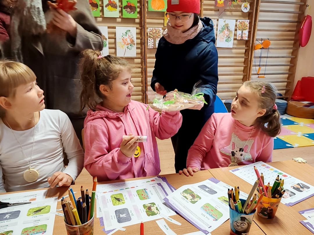 Dzień Życzliwości i Pozdrowień | Uczennica częstuje przedszkolaki ciastkami.jpg