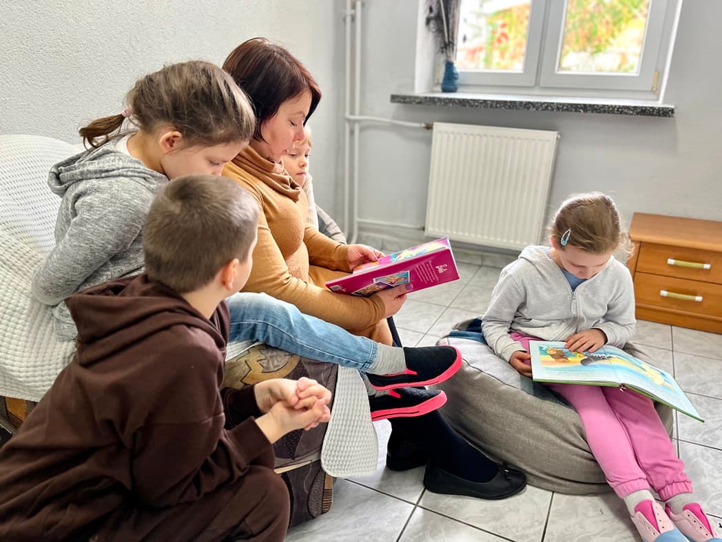 Zrób sobie przerwę na czytanie | nauczyciej siedzi na fotelu i czyta dzieciom bajki.jpg