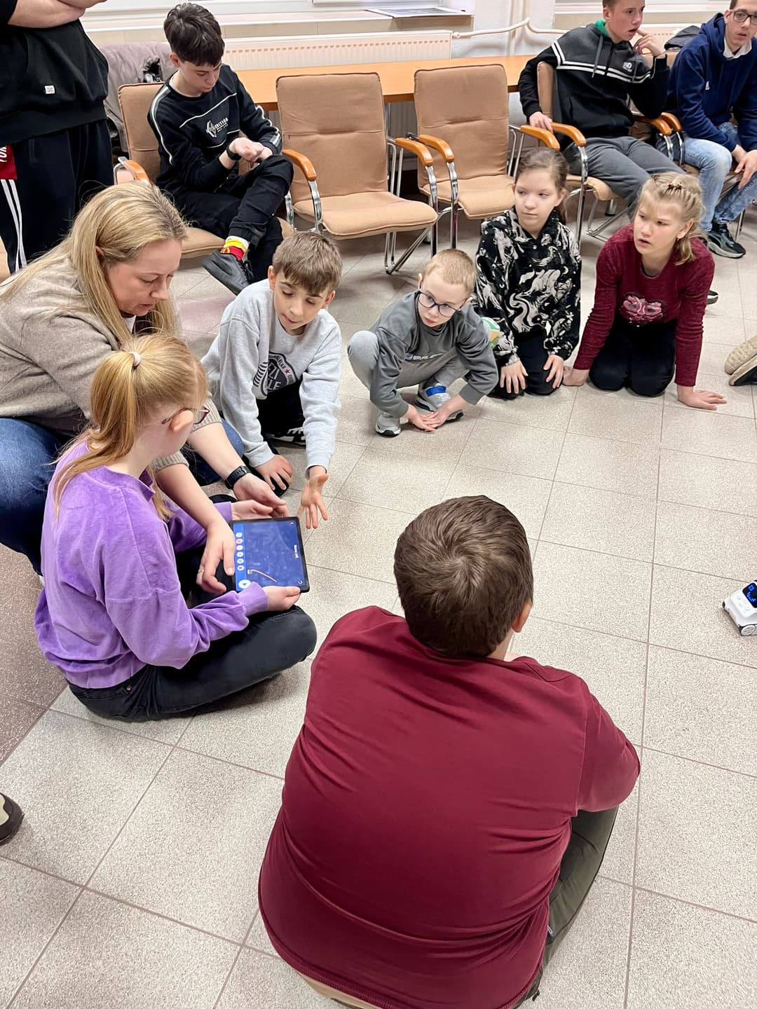 ROBOTYKA | Dzieci siedzą w kole, dziewczynka trzyma tablet sterujący robotem.jpg