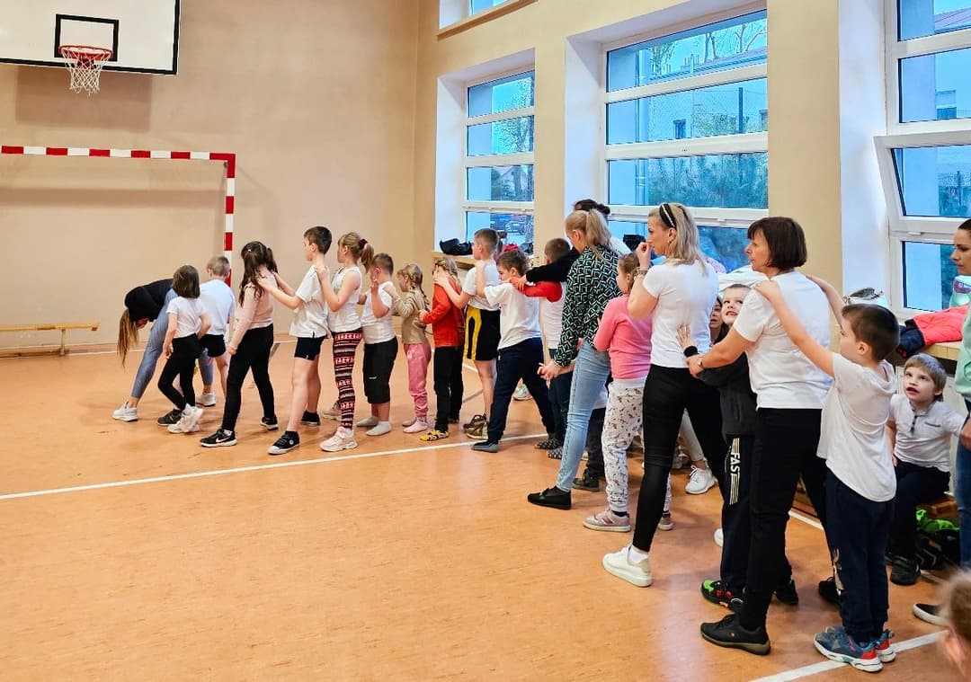 Ćwiczenia ruchowe z mistrzynią Polski w kickboxingu | Dzieci i nauczyciele tworzą pociąg, trzymając się za ramiona.jpg