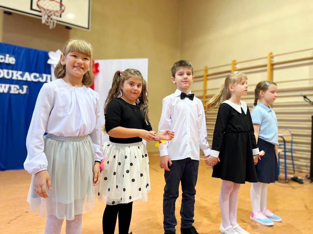 Świętujemy Dzień Edukacji Narodowej | Oświętnie ubrane dzieci stoją w rzędzie na scenie.JPG