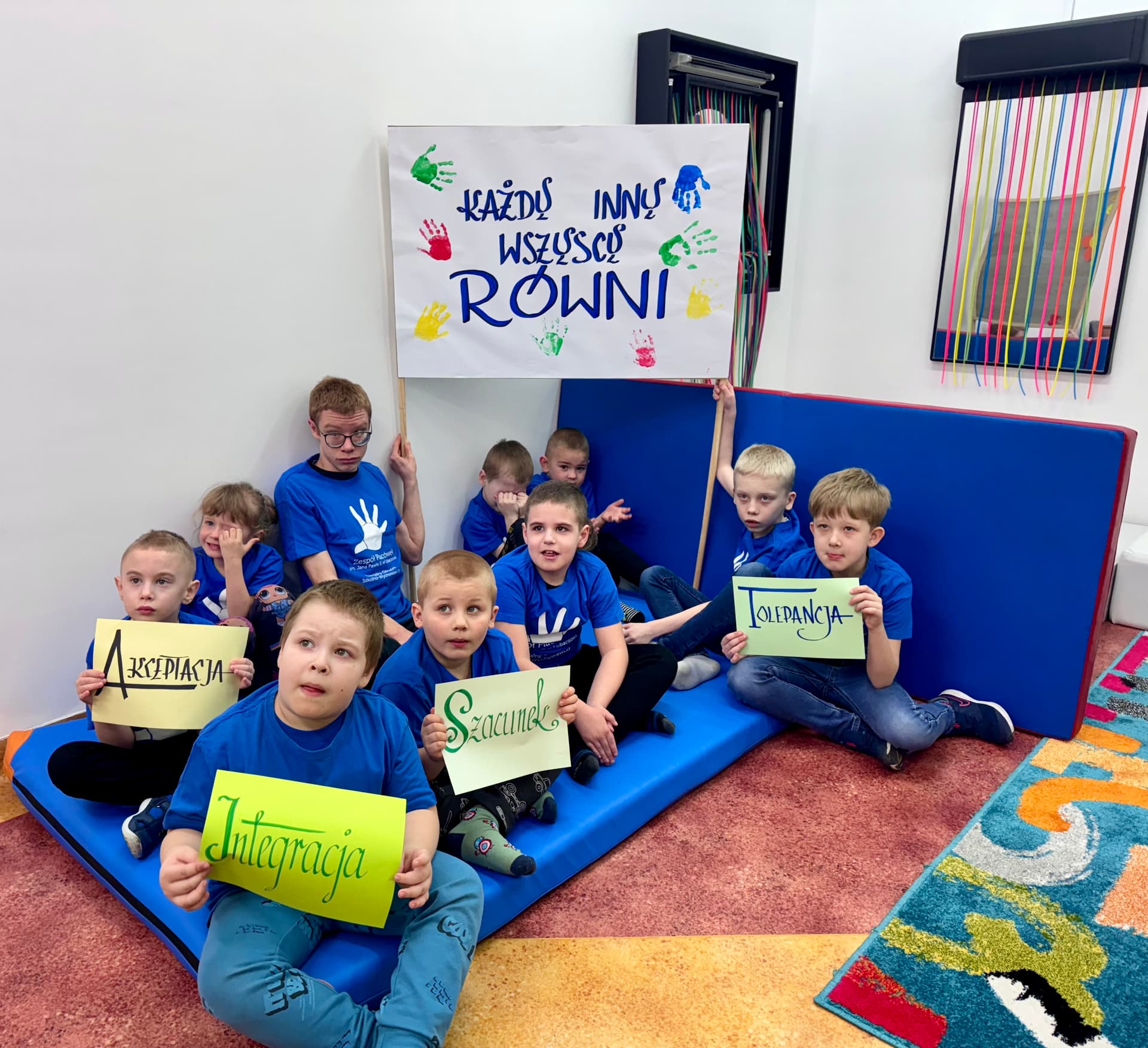 Światowy Dzień Świadomości Autyzmu | GŁÓWNE Dzieci siedzą na materacu i trzymają transparent i hasła (2).JPG